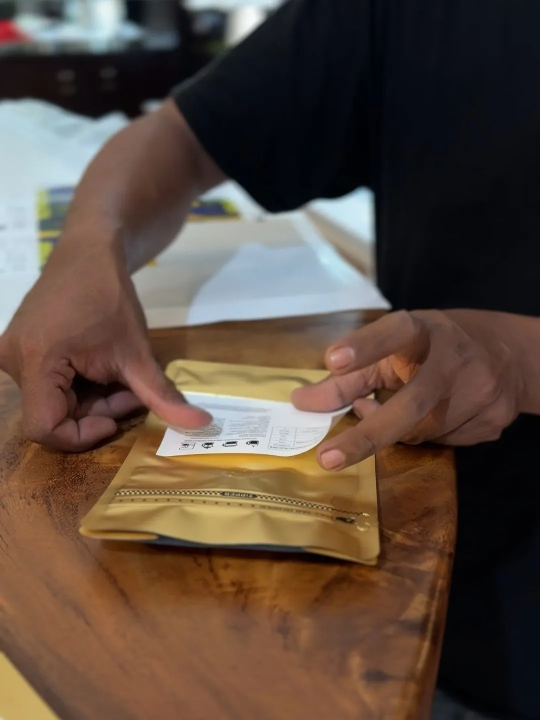 Hands applying a label to a gold coffee bag